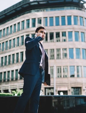 Resmi kıyafetli ciddi bir adam iş arkadaşına telefon edip cep telefonuyla iletişim kuruyor. Türk erkek sahibi hesap bakiyesini kontrol etmek için operatörle konuşuyor.