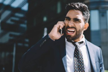 Öfkeli yetişkin erkek yönetmen, uluslararası arama sırasında kötü haber aldığı için kızgın. Akıllı telefon uygulaması ile konuşurken çalışana bağıran, suratında çılgın bir ifade olan adam.