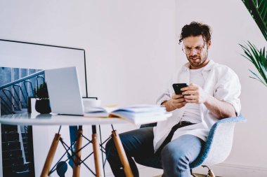 Kafkas erkek blogcu cep telefonu uygulaması üzerinden sosyal ağlarda bir sonraki yayın için bilgi arıyor, akıllı telefon ve dizüstü bilgisayarla bilgi paylaşan genç pozitif hipster.