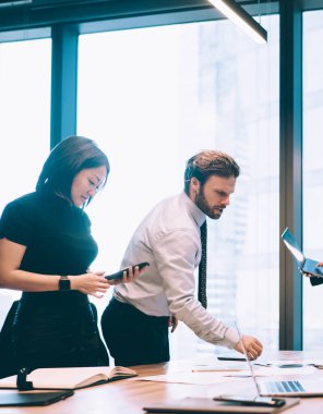 Şirket çalışanları, akşam geç saatlerde ofis içi toplantılarında finansal girişim projesiyle ilgili fikirleri tartışıyor ve görüşlerini paylaşıyorlar. Masada iletişim kuran ve çalışan bir grup iş adamı.