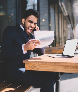 Resmi olarak kızgın olan Türk adam, muhasebe raporundaki verileri incelerken öfkeli hissediyor. Çalışanlara sesleniyor ve dışarıda boş ekran alanıyla birlikte netbook ile otururken kötü iş için bağırıyor.