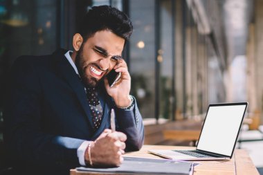 Saldırgan erkek bankacı, cep telefonuyla çalışan ile iletişim kurarken bilgisayarını kopyalama alanı olan dizüstü bilgisayarla masaya vuruyor. Öfkeli adam konuşan asistan ve kızgın hissediyor.