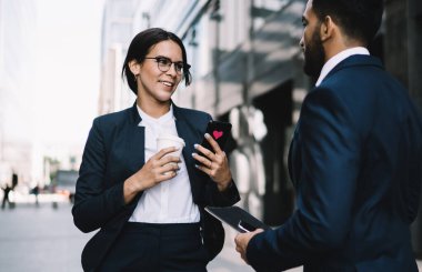 Finans bölgesindeki ofis binalarının yakınında fikirleri ve yaratıcı stratejileri tartışan gülümseyen meslektaşlar, kahve saatinde iletişimin keyfini çıkaran mutlu erkek ve kadın girişimciler.