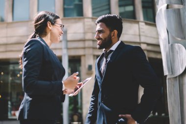 Mutlu erkek ve bayan meslektaşlar iş ortaklarıyla iş görüşmesi yapmadan önce canlı iletişimin keyfini çıkarıyorlar. Birlikte komik anlarda iş birliği yapıyorlar. Farklı gülen erkekler ve kadınlar açık havada.