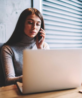 Profesyonel metin yazarı kahve dükkanında otururken mesafe iş zevk ve konuşma için cep telefonu yeni bir uygulama kullanarak patron ile konuşurken, netbook üzerinden pensive kadın klavye mesajı