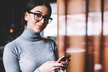 Gözlüklü neşeli blogcu portresi cep telefonuyla yeni yayın yaparken kameraya bakıyor, modern cep telefonu teknolojisini elinde tutan mutlu hippi kız dinleniyor.