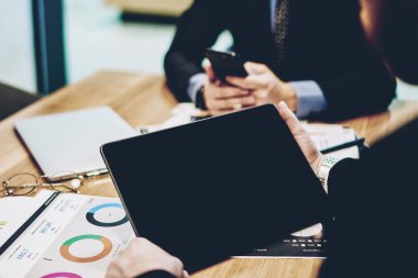 Resmi giyinmiş iki işadamı ofis içi toplantılarında fikirleri açıklamak için modern teknolojiyi kullanıyorlar. Erkekler çalışanı dijital tablet aygıtındaki uygulamayı güncelliyor, iş arkadaşları çalışıyor