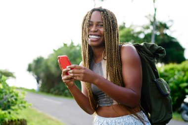 Wanderlust yolculukta hedef yer arama yeri için yer uygulaması kullanırken kamera gülümseyen elinde akıllı telefon gadget ile neşeli heyecanlı hipster kız yarım uzunlukta portre