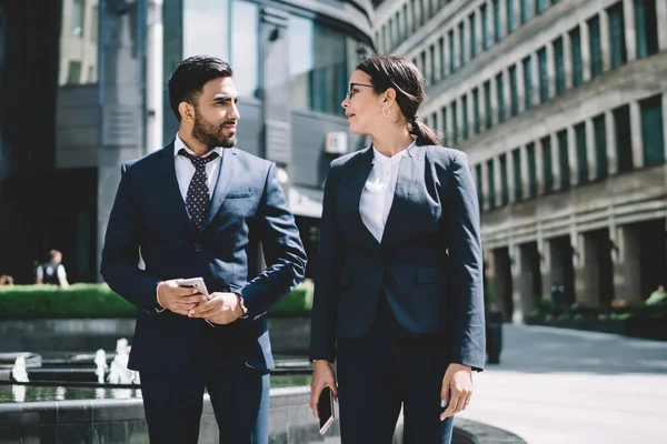 stock image Multicultural male and female entrepreneurs walking around city street in downtown and communicate about upcoming startup project,diverse business people in formal suit strolling in financial district