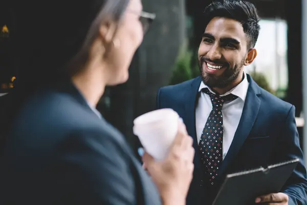 Successful male and female business experts recalls to pleasant moment together during break from work, smiling man in formal elegant wear talking with colleague while spending time outdoors