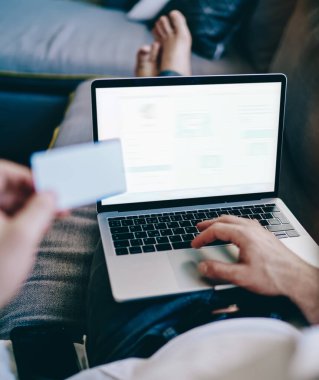 Yetenekli bir adamın kanepede dinlenmesi ve internet tarayıcısındaki yeni web mağazası hakkında bilgi araması. Erkek, reklam için boş ekran alanı olan dizüstü bilgisayarda 4G bağlantısı kullanıyor.