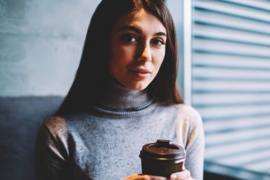 Çekici kız öğrenci coworking alanında dizüstü bilgisayar ile oturan kahve molası zevk kamera bakıyor, kafeteryada dinlenirken fincan ile poz kafkas güzel esmer kadın