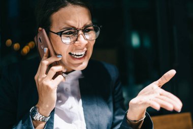 Görme düzeltmesi için optik gözlüklü kızgın kadın dizüstü bilgisayarla şirket muhasebe raporuyla e-posta aldı ve şirket müdürünü bağırıp çağırarak öfkeden kudurdu.