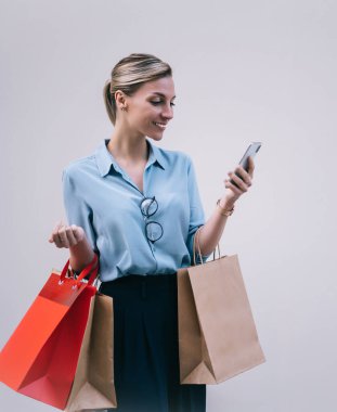 Tarz sahibi beyaz alışverişçiler ellerinde kağıt torbalarla akıllı telefon uygulamalarıyla internet mesajlaşmalarının keyfini çıkarıyorlar. Reklam alanının yakınlarındaki mutlu hipster kız sohbetleri.