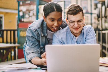 Mutlu çok kültürlü çiftler internet sitesinde oturup kablosuz internet kullanarak komik videolar izliyorlar. Afro-Amerikan yenilikçi kız, Kafkasyalı kızla birlikte yayın yapıyor.