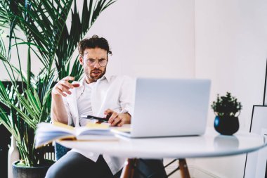Sosyal ağlarda dizüstü bilgisayar okuyarak uzaktan çalışan kafası karışık erkek serbest çalışan ciddi bir beyaz adam, online iş için modern netbook kullanıyor ve dosyaları indiriyor.