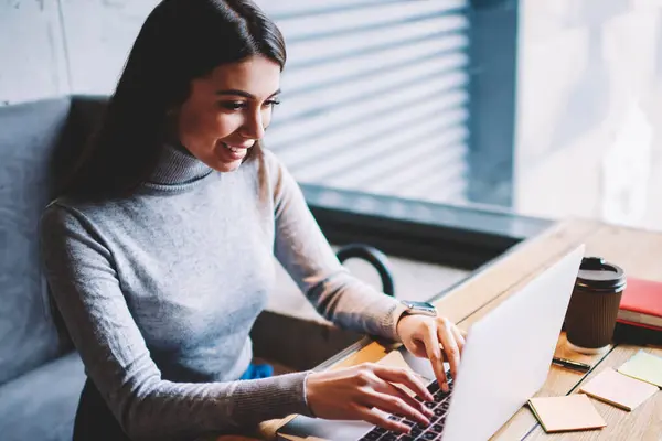 Kafeteryada sabah kahvesi sırasında bilgisayarda online komedi gösterisi izleyen neşeli gülümseyen hipster kız, mutlu kadın yazılım geliştiricidizüstü bilgisayar üzerinden çalışan ve mola sırasında komik videolar seyir