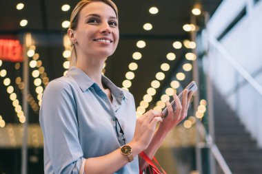 Alışveriş çantaları ve akıllı telefonları elinde tutan ve Kara Cuma boyunca gözlerini kaçıran neşeli bir kadın. Çekici gülümseyen hippi kız boş zamanlarında reklam alanında beklerken telefon bekliyor.