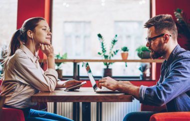 Akıllı telefon uygulaması ve elektronik kulaklıkla en sevdiği müzik listesini dinleyen güzel bayan melodinin yan görüntüsü ve dizüstü bilgisayarla internet iletişimini tercih eden erkek arkadaşına bakmak