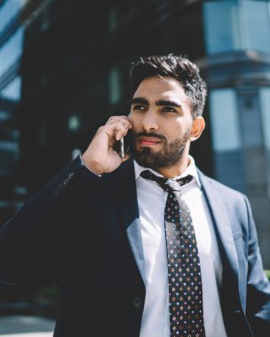 İspanyol sakallı adam iş seyahati sırasında patronla uluslararası konuşma yapmak için dolaşım bağlantısını kullanıyor, ciddi bir erkek girişimci akıllı telefondan operatöre başvuruyor.