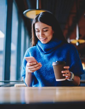 Kaygısız kadın hipster kız modern cep telefonu üzerinden arkadaşları ile sohbet ve kahve ile fincan tutarak, başarılı blogger iletişim ve cep telefonu numarası arama için uygulama yükleme
