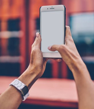 İnternet içeriğiniz için boş ekranlı modern akıllı telefonu tutan ve fotoğraf çekmeye odaklanan kadın elleri görüntüsü. Web siteniz için kopyalama alanı olan dijital cep telefonu