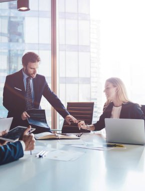 Profesyonel finans uzmanları ofis içi işbirliği sırasında rapor detaylarını tartışıyor, olgun erkek ve kadın şirket yöneticileri masaüstü yakınlarındaki bilgilerde birlikte beyin fırtınası yapıyorlar