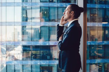 Erkek girişimci, ofis içi akıllı telefon uygulaması aracılığıyla yatırım yapma fikirleri hakkında meslektaşına danışıyor, iş adamı banka irtibat hizmetleri operatöründeki hesaptan parayı kontrol ediyor