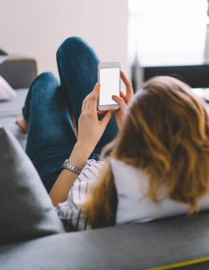 Genç bir kadının kendi odasındaki rahat kanepeye uzanması, şık bir iç mekan ve arkadaşlarıyla internette sohbet etmesi.