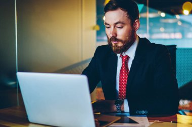 Resmi giyinmiş dalgın sakallı girişimci masaüstünde otururken modern dizüstü bilgisayarda iş webinar 'ı izliyor. Dijital netbook' ta çalışan konsantre erkek girişimci, e-posta yazıyor.