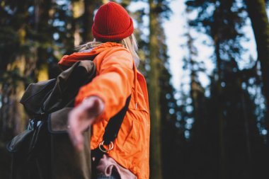 Turistik sırt çantalı kadın gezginin dağlara yaptığı yürüyüş sırasında orman çevresindeki ipuçlarına el uzatması, aktif bir kadının eğlence için ulusal parkta zaman geçirmesi.