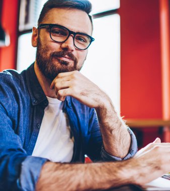 Bedava kafeterya internetine bağlı dizüstü bilgisayar cihazında video araması beklerken kameraya bakarken görüş düzeltmesi için şık gözlüklü yetenekli beyaz adamın portresini kapat.