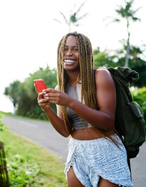 Wanderlust yolculukta hedef yer arama yeri için yer uygulaması kullanırken kamera gülümseyen elinde akıllı telefon gadget ile neşeli heyecanlı hipster kız yarım uzunlukta portre