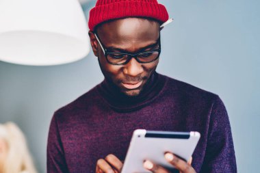 Takipçilerden gelen e-postaları kontrol eden dalgın Afrikalı Amerikalı hippi dijital tablet ve Wi-Fi kullanarak internet sayfasında yayınları ve multimedya dosyalarını paylaşıyor.