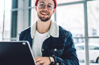 Gülümseyen erkek serbest girişimci yeni bir proje üzerinde çalışıyor. İnternet araştırmacılarını laptop bilgisayarı ve kablosuz internet bağlantısı kullanarak verileri analiz etmeye zorluyor.