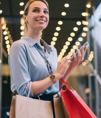 Alışveriş çantaları ve akıllı telefonları elinde tutan ve Kara Cuma boyunca gözlerini kaçıran neşeli bir kadın. Çekici gülümseyen hippi kız boş zamanlarında reklam alanında beklerken telefon bekliyor.