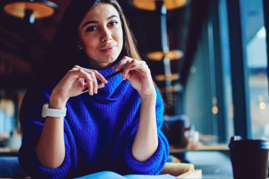 Düşünceli kız öğrenci kalem tutarken sınav hakkında düşünme ve kapalı kahve molası zevk, pensive hipster kız ders kitabında notlar yazarken kafeterya da oturan uzak bakıyor