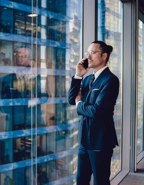 Caucasian male financial director of company making important smartphone conversation with business partner, mature lawyer formally dressed communicating with operator via mobile application