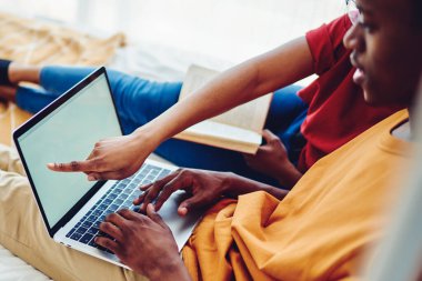 Genç Afro-Amerikan evliliğinin internetten alışveriş için dizüstü bilgisayarla internete bağlanan görüntüsü. Aşıklar internet üzerinden rezervasyon yapıyor ve fikirleri tartışıyorlar.