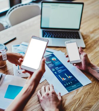 İnternet reklamınız veya web siteniz için boş ekran alanına sahip modern akıllı telefon aygıtlarını tutan ve medya dosyaları aracılığıyla bilgi paylaşmak için bluetooth bağlantısı kullanan ellerin kesilen üst görünümü