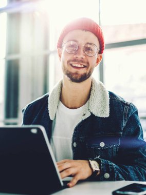 Modern tablet klavye aksesuarına el ele tutuşan neşeli hippi adam kameraya poz verirken mutlu genç bir erkek şehir kahvecisinde serbest çalışıyor. Çevrimiçi bankacılık kullanıyor.