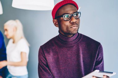 Düşünceli Afrikalı Amerikalı hippi sosyal ağlarda kişisel blog 'da dijital tablet ve wifi kullanan yaratıcı meslektaşlarıyla modern ofiste zaman geçirme fikirleri üzerine kafa yoruyor.
