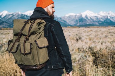 Sırt çantalı, ciddi bir beyaz erkek turist hafta sonunu Alpler 'deki dağların tepesine çıkmak için harcıyor. Genç adam, yüksekliğe giden en iyi rotalara odaklanmış ve çevreye bakıyor.
