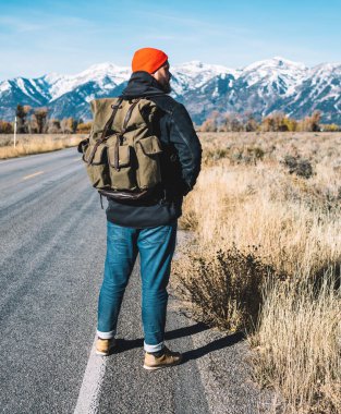 Sırt çantalı turist doğa ortamında yola çıkıyor, erkek yürüyüşçüye bakıyor ve dağlara yolculuk boyunca temiz havanın tadını çıkarıyor, dinleniyor ve tatil kavramının tadını çıkarıyor.
