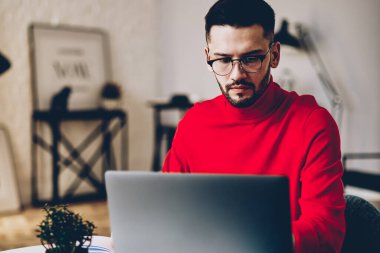 Görme düzeltmesi için gözlüklü genç adam laptop bilgisayarından özel ders izliyor kablosuz internet bağlantısı kullanıyor, netbook ile uzaktan çalışan genç hippi çocuk