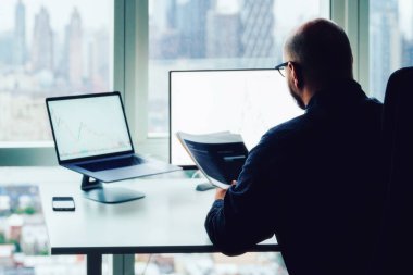 Gökdelenlerde oturan işadamlarının arka planında ofis içi masaüstü bilgisayarları ve finansal grafikler ve bilgi istatistikleri görülüyor. Borsa ve blok zinciri kriptosu yatırımlarının analizi