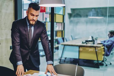 Takım elbiseli başarılı bir CEO iş planını açıklıyor ve modern dokunmatik pedi iş için kullanan yaratıcı erkek çalışanlara iş veriyor. Ofisteki tüccarla iletişim kuran finans şirketinin sahibi.