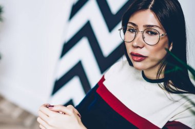 Optik gözlüklü düşünceli kadın gözlerini kaçırıyor ve internet siteniz ya da reklamınız için boş ekran alanı olan dizüstü bilgisayarla uzaktan yakından ilgili bilgiler üzerinde kafa yoruyor.