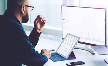İşadamı olası riskleri ve kârları hesaplamak için finans piyasasını araştırıyor. Erkek ekonomist muhasebe parası ve ofis bilgisayarındaki dizüstü bilgisayardaki araştırma istatistikleri. Değiş tokuş sırasında alıntılar
