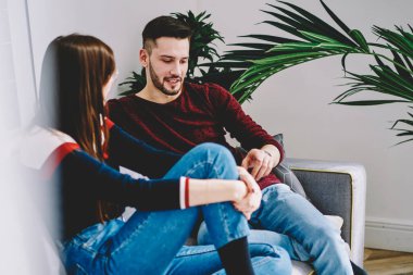 Birbirine aşık çiftler ilişki hakkında iletişim kurarken rahat ev içlerinde vakit geçiriyorlar, genç evlilikler modern apartman dairesinde sohbet ediyorlar rahat bir koltukta dinleniyorlar.